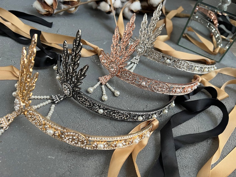 May include: Four gold, silver, black, and rose gold headbands with pearl accents and leaf designs. The headbands are tied with black and beige ribbons.