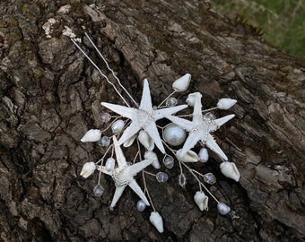 May include: A set of two white starfish hair pins with pearl and shell accents. The pins are attached to a silver wire with small white beads and shells.