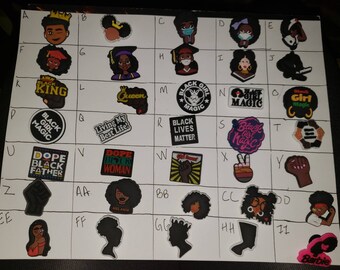May include: A collection of iron-on patches featuring various designs related to Black culture, including phrases like "Black Girl Magic", "Black Lives Matter", and "Dope Black Father", as well as images of crowns, fists, and silhouettes.