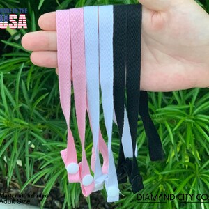 Puede incluir: Cinco correas de algod&oacute;n de diferentes colores con hebillas ajustables. Las correas son de color rosa, blanco, negro y dos correas negras m&aacute;s. Las correas est&aacute;n hechas en los EE. UU. El texto "DIAMOND CITY CO." es visible en la imagen.