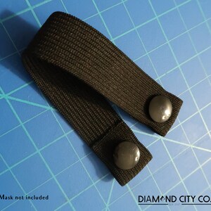 K&ouml;nnte beinhalten: Schwarzes Gummiband mit zwei schwarzen Kn&ouml;pfen. Maske nicht im Lieferumfang enthalten. DIAMOND CITY CO. EST 2017.