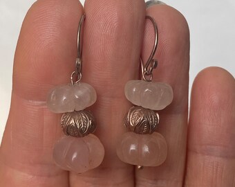 May include: A pair of silver dangle earrings with three pink quartz beads on each earring. The beads are carved in a pumpkin shape.