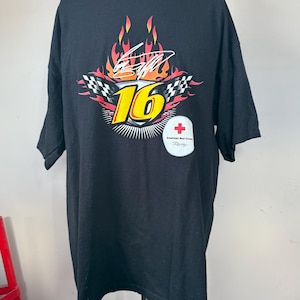 May include: Black t-shirt with a racing design. It features the number 16 in yellow, a checkered flag, and flames. Includes the American Red Cross Racing logo. The shirt has short sleeves.