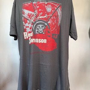 May include: Dark gray t-shirt featuring a red and white graphic of a race car wheel, signature, and the name "Reed Sorenson." The design includes a checkered flag and the number "41."