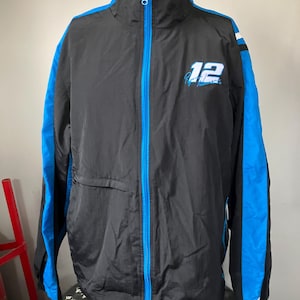 May include: Black and blue windbreaker jacket with a white and blue stripe down the sleeves. The jacket has a zipper closure and a small pocket on the left side. The number "12" and a signature are embroidered on the front.