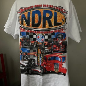 May include: White t-shirt with a colorful graphic of drag racing cars and the text "NOSTALGIA DRAG RACING LEAGUE NDRL NDRL-IAM CHAMPIONSHIP SERIES".