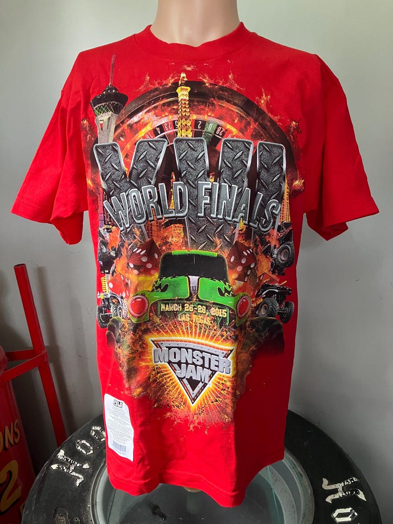 Puede incluir: Camiseta roja con un estampado gr&aacute;fico de un cami&oacute;n monstruo, una ruleta de casino y el texto "XVI World Finals" y "Monster Jam". El texto "March 26-28, 2015 Las Vegas" tambi&eacute;n est&aacute; impreso en la camiseta.
