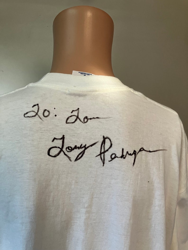 May include: White t-shirt with black writing on the back. The writing says "20:20" and "Tony Parker".