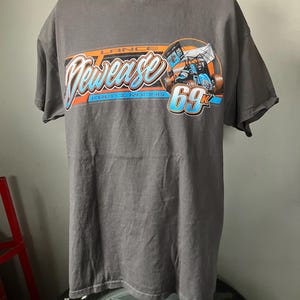 May include: A gray t-shirt with a graphic of a race car and the text "Lance Dewease Krenz Racing 69K" in orange, blue, and white.