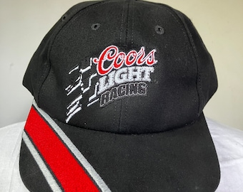 May include: Black baseball cap with a red and white stripe on the brim. The front of the cap features an embroidered logo that says "Coors Light Racing."
