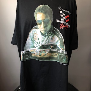 May include: Black t-shirt with a photo of Darrell Waltrip, a race car driver, wearing sunglasses and a racing suit. The shirt has the text "Western Auto Racing" and a checkered flag design.