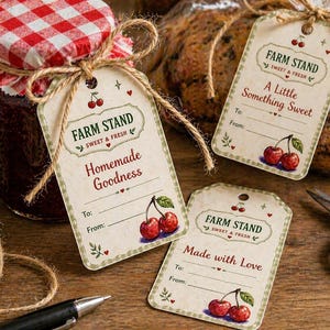 Op de afbeelding: Een pot zelfgemaakte jam met een rood-wit geruit deksel, vastgebonden met touw, en drie decoratieve labels. De labels lezen "Farm Stand Sweet & Fresh" en bevatten kersenillustraties. De labels zeggen "Homemade Goodness", "A Little Something Sweet" en "Made with Love".