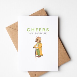 May include: A greeting card featuring a cartoon illustration of a dog wearing a hat and smoking a pipe. The text on the card reads "Cheers to the birthday boy."