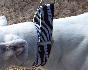 May include: A white and black zebra print dog collar with a silver metal loop.