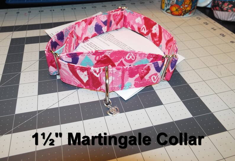 May include: A pink and white 1 1/2 inch martingale dog collar with a heart print and a silver crown charm.