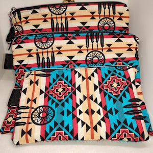 May include: Three zippered pouches with a Native American inspired geometric pattern in shades of red, orange, blue, black, and white. The pattern includes dreamcatchers and feathers.