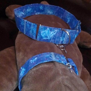 K&ouml;nnte beinhalten: Ein blaues und wei&szlig;es Hundehalsband mit einem silbernen D-Ring. Das Halsband ist aus Stoff und hat ein Schmetterlingsmuster.