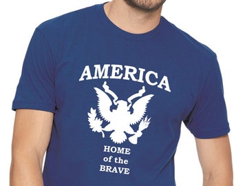 May include: A royal blue t-shirt with a white graphic of the American bald eagle and the words "AMERICA HOME of the BRAVE".