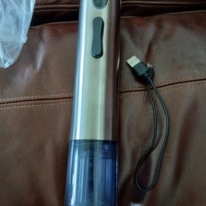 May include: A stainless steel electric wine bottle opener with a black button and a blue transparent lower section. A black USB charging cable is attached. The opener is designed for easy wine bottle opening.