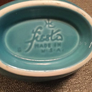 May include: A turquoise blue Fiestaware oval dish with a white rim. The bottom of the dish has the Fiestaware logo and "Made in USA" printed in white.