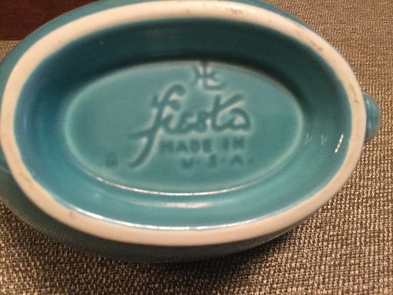 May include: A turquoise blue Fiestaware oval dish with a white rim. The bottom of the dish has the Fiestaware logo and "Made in USA" printed in white.