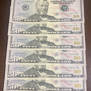 May include: Several fifty-dollar bills are displayed, each featuring a portrait of Ulysses S. Grant. The bills are green and black, with the number 50 prominently displayed. The text "FIFTY DOLLARS" is visible on each bill.