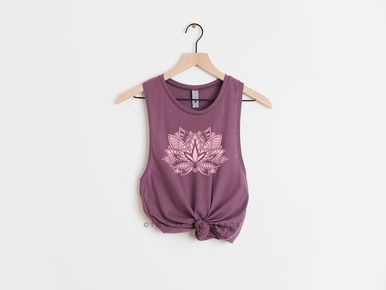 Puede incluir: Un top sin mangas morado con un dise&ntilde;o de flor de loto rosa. El top est&aacute; atado en la parte delantera.