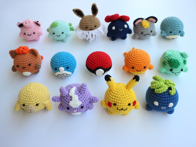 May include: A collection of colorful, crocheted plush toys, each designed to resemble a different character. The toys are round and have various features, including ears, eyes, and other distinguishing characteristics. The toys are in various colors, including pink, blue, yellow, and brown.
