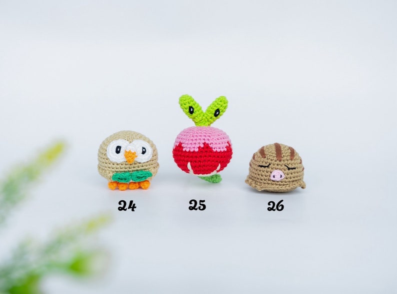 May include: Three crocheted amigurumi figures: an owl, a radish, and a sleeping pig. The owl is tan with orange feet and green accents. The radish is pink and red with green leaves. The pig is tan with brown stripes.