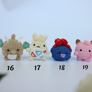 May include: Four handmade crochet figures in a row. The figures are in various colors, including tan, white, blue, and pink. Each figure has unique features, such as ears, bows, and facial expressions. Numbers 16, 17, 18, and 19 are below each figure.