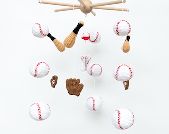 May include: A wooden baby mobile with crocheted baseballs, bats, and a glove hanging from it. The mobile is white with red stitching on the baseballs.