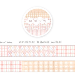 Może przedstawiać: Rolka taśmy washi w r&oacute;żowe i pomarańczowe wzory z nadrukiem "奶咖少女" na etykiecie. Taśma ma 1,5 cm szerokości i 10 metr&oacute;w długości.