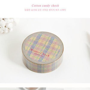 May include: A roll of washi tape with a plaid pattern in shades of pink, blue, and yellow. The tape is labelled "Winter Check" and "masking tape".