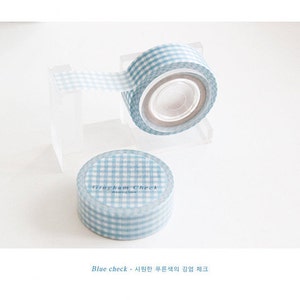 May include: A roll of blue and white gingham patterned washi tape. The tape is on a clear plastic dispenser. The text "Graham Check" is printed on the tape.
