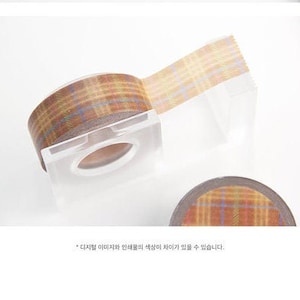 May include: A roll of brown and beige patterned washi tape with a plaid design. The tape is on a clear plastic dispenser.