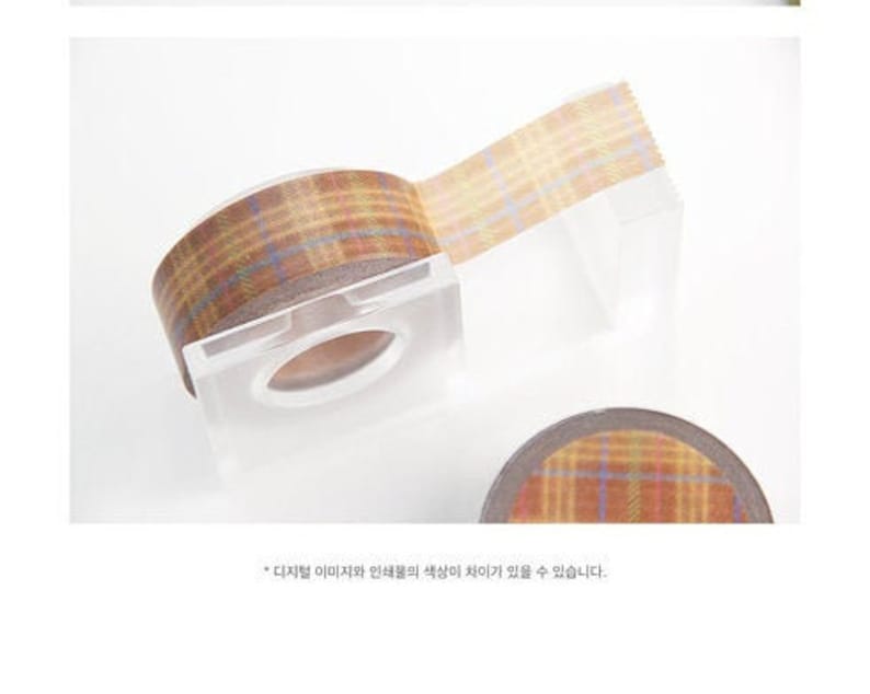 May include: A roll of brown and beige patterned washi tape with a plaid design. The tape is on a clear plastic dispenser.