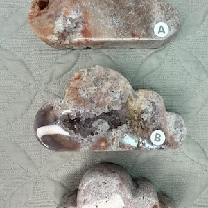 May include: Three cloud-shaped decorative stones in shades of brown, grey, and white. Each stone has a unique texture and internal crystalline structure. The stones are labelled A, B, and C.