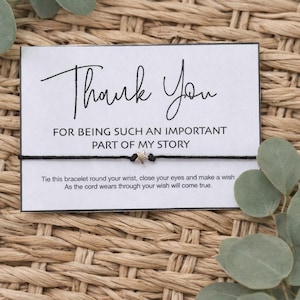 May include: A black cord bracelet with a small star charm, presented on a card that reads "Thank You" in elegant script. The card also includes the text "FOR BEING SUCH AN IMPORTANT PART OF MY STORY."