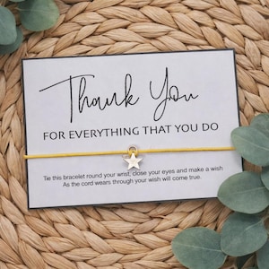 May include: A greeting card with the words "Thank You" and "FOR EVERYTHING THAT YOU DO" in black script. A yellow cord bracelet with a star charm is attached. The card includes instructions. The background is woven.
