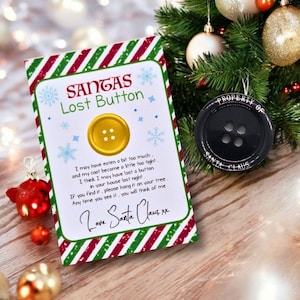 Op de afbeelding: Een kerstornamentenset met een kaart en een knopvormige decoratie. De kaart leest "Santa's Lost Button" met een gouden knopillustratie. Het zwarte knopornament zegt "Property of Santa Claus".
