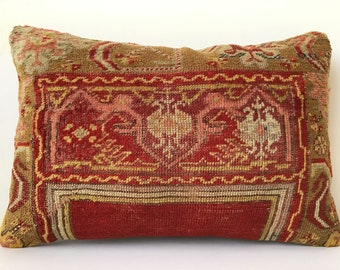 Peut inclure: Un coussin rectangulaire en tissu à motifs rouges, dorés et crème. Le coussin présente un motif traditionnel de kilim turc.