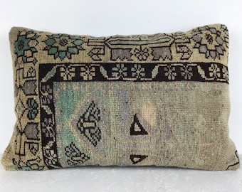 May include: A rectangular throw pillow with a vintage, hand-woven design. The pillow features a faded green and brown geometric pattern with a black border.