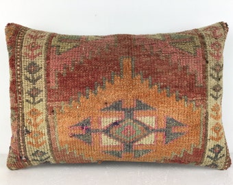 Peut inclure: Un coussin rectangulaire avec un motif géométrique coloré dans des tons de rouge, orange, vert et beige. Le coussin a une texture tissée et une bordure à franges.
