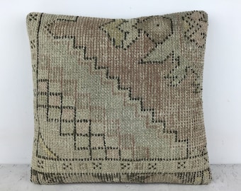 May include: A square pillow with a woven pattern in shades of brown, beige, and black. The pillow has a geometric design with a central square and a border.