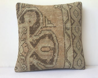 May include: A square cushion with a brown and beige woven pattern. The cushion features a geometric design with a central motif.