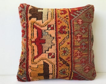 Peut inclure: Un coussin carré avec un motif géométrique rouge, orange et marron. Le coussin est fait d'un tissu tissé avec une surface texturée.