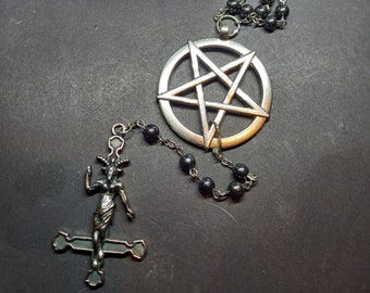 May include: A silver-toned necklace featuring a circular pentagram pendant and a series of dark, metallic beads. The chain is accented with smaller pentagram charms and terminates in a pendant depicting a horned figure atop an inverted cross.