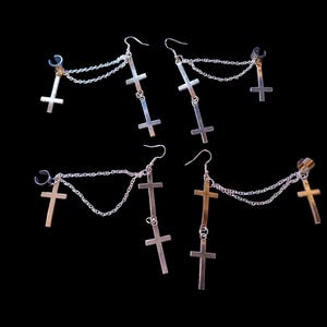 May include: A set of four silver cross earrings with chains. Each earring has three cross charms and a clip-on ear cuff.