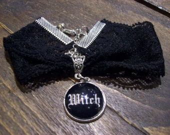 May include: Black lace choker necklace with a silver charm that says "Witch" in a gothic font.