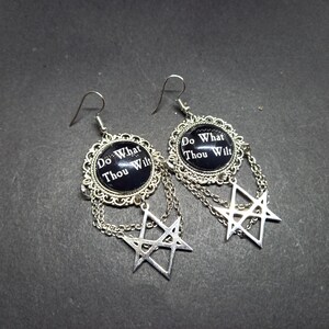 May include: A pair of silver earrings with a black pendant featuring the text "Do What Thou Wilt" and a pentagram charm.